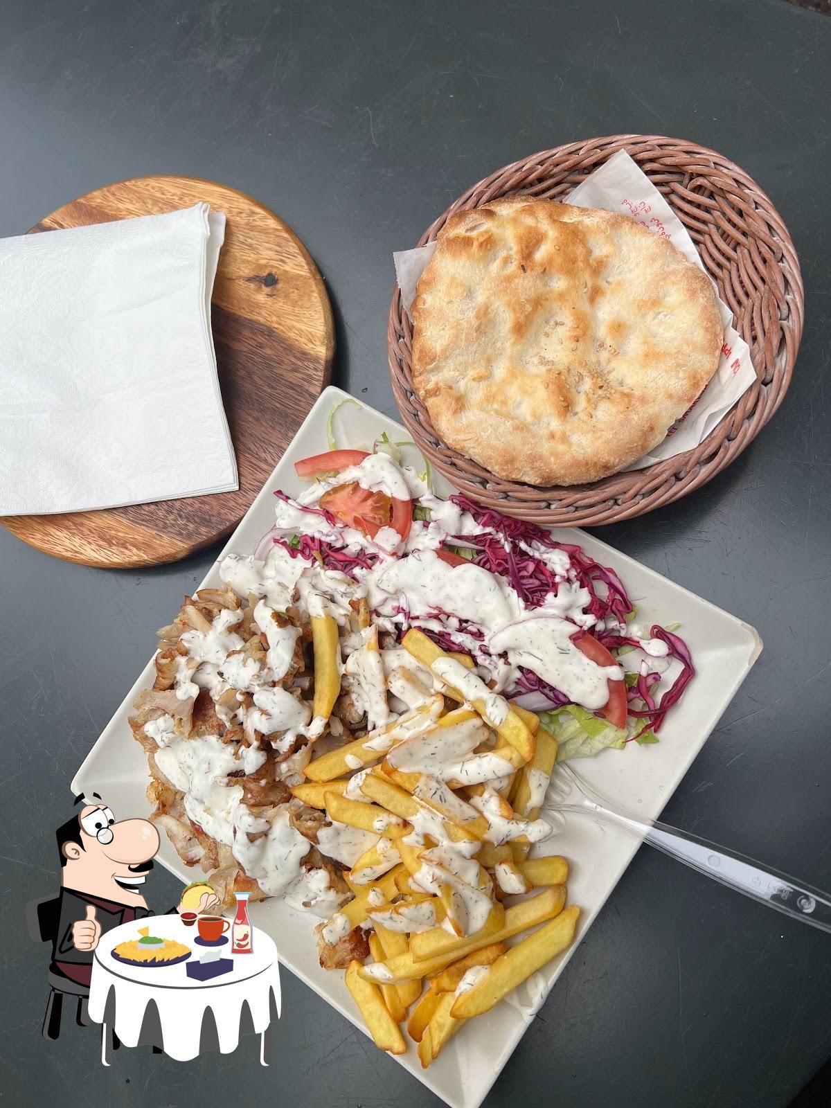 Piatto bianco di kebab di pollo con patatine, cavolo rosso, pomodoro e salsa allo yogurt, pane pita in cestino di vimini
